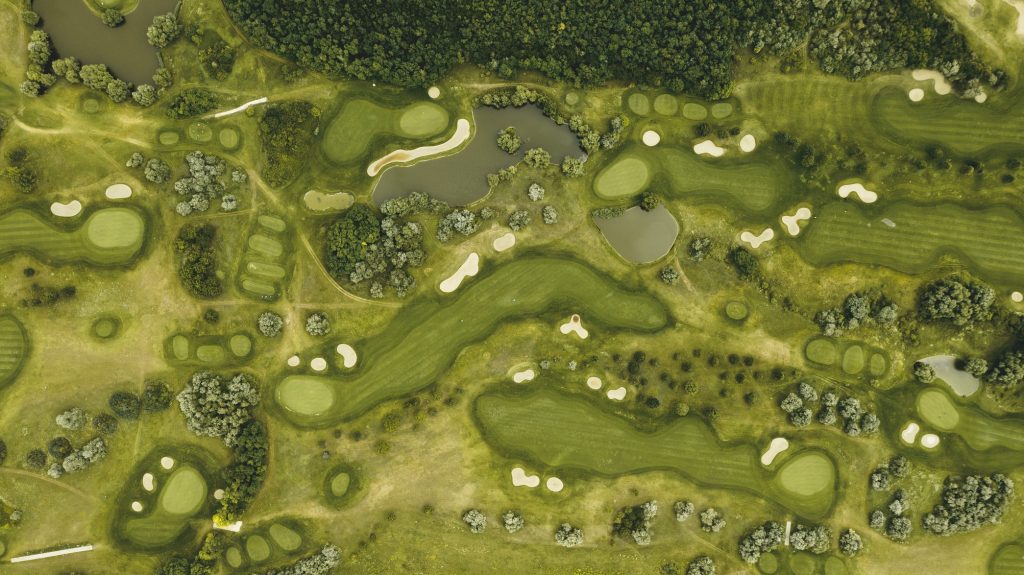 Schematische Übersicht eines Golfplatzes mit Fairways, Grüns und Hindernissen.